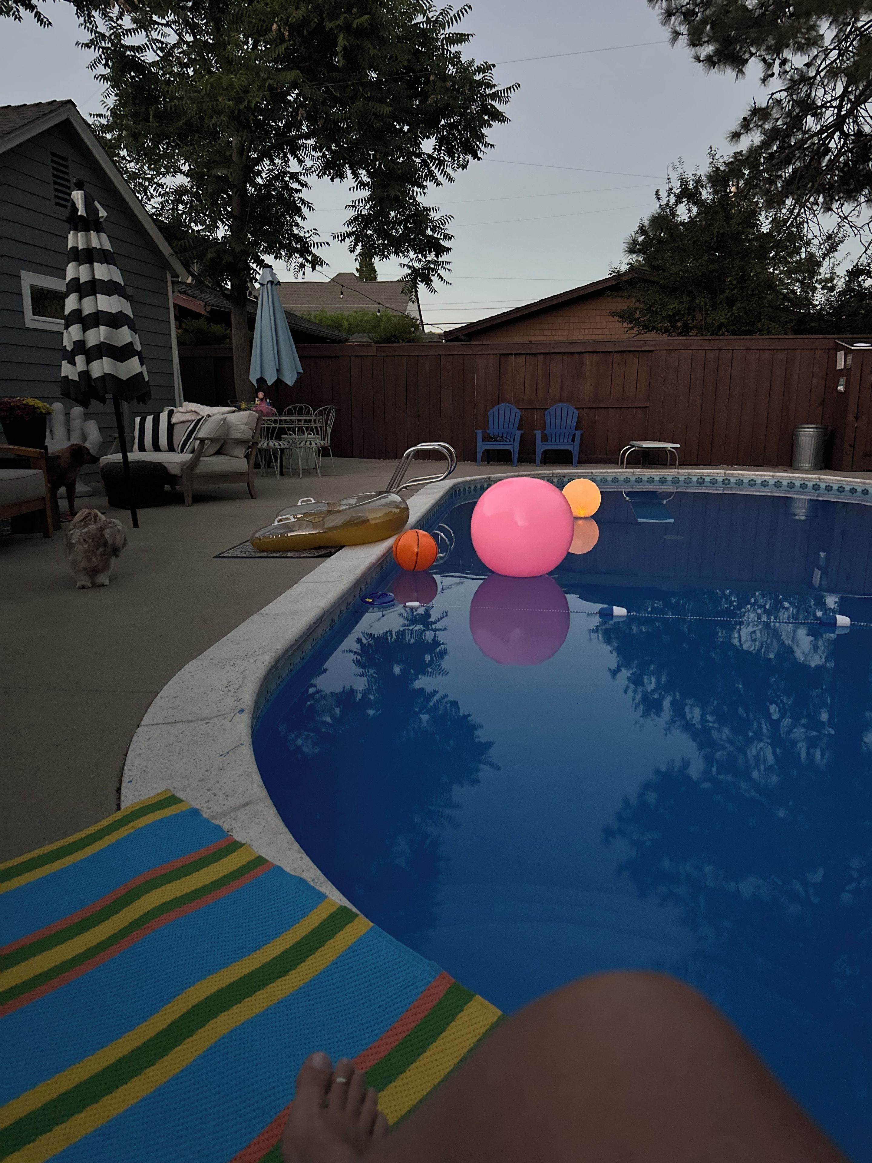 Une piscine avec des jeux gonflables et un espace détente avec des chaises et une table.