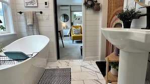 A bathroom with a freestanding bathtub, a sink, and a mirror. - Luxury King Studio • Heated Floors • Soaking Tub • Seasonal Pool Access (Yreka)