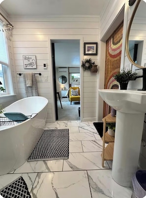 A bathroom with a freestanding bathtub, a sink, and a mirror.