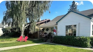 A white house with a porch, a flag, and a well-maintained lawn. - Luxury King Studio • Heated Floors • Soaking Tub • Seasonal Pool Access (Yreka)