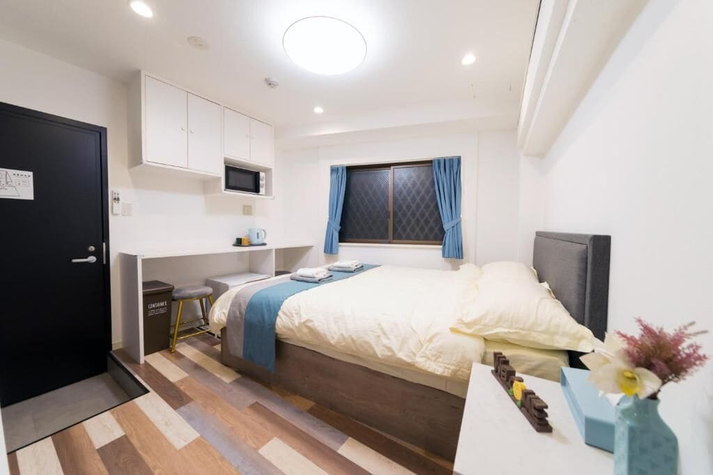 A compact bedroom with a bed, bedside table, and a small desk area.