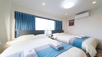 A hotel room with two beds, a large window with curtains, a nightstand, and a wall-mounted air conditioner.