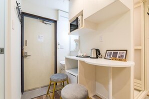 A compact kitchenette with a microwave, a coffee maker, and a small table with a 'Welcome' sign.