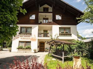 Ein zweigeschossiges Gebäude mit Balkonen, einer Holzfassade und einem Schild, das es als Pension kennzeichnet.