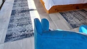 Une chambre avec un plafond en bois, un lit, une chaise bleue et un bureau.