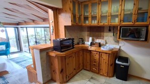 Une cuisine avec des meubles en bois, un four à micro-ondes et une poubelle.