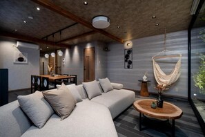 Ein modernes Wohnzimmer mit einer Couch, einem runden Holztisch und einem Hängesessel.