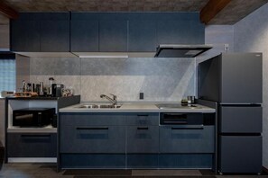 Eine moderne Küche mit dunklen Schränken, einem Edelstahl-Kühlschrank und einer eingebauten Mikrowelle.