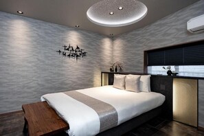 Ein modernes Schlafzimmer mit einem großen Bett, einer hölzernen Bank, einer Wandleuchte und einem Fenster mit Jalousien.