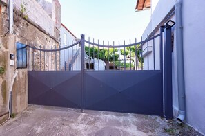 A gated entrance with a metal gate, a concrete wall, and a building with a white facade. - Vachlas Family House 1912 - Balcony - BBQ - Nature near Manikia Climbing Area (H29W+W99 Ag. Vlasios)