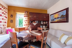 Una sala de estar acogedora con una mesa de comedor, sillas, un sofá, una estantería y un cuadro en la pared.
