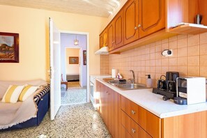 A kitchen with wooden cabinets, a countertop, and a sink. There is a dining area with a table and chairs.