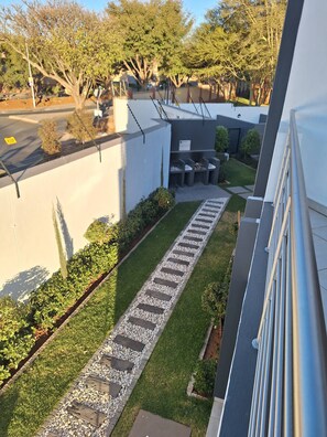 A modern building with a paved pathway, greenery, and a clear sky. - Zalari Luxe 93 on New, 1 bed, Central & Premium Comfort (Midrand)