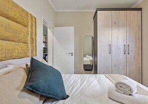 Quarto com cama, almofadas, guarda-roupa e espelho.