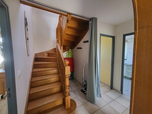 Eine Holztreppe mit Handlauf, ein rotes Objekt auf der Zwischenebene und ein Staubsauger im Raum.