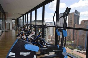 A gym with stationary bikes and treadmills, large windows with a city view. - Modern Studio Apartment (Bogotá)