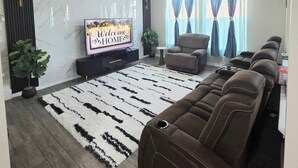 Un salon moderne avec un canapé, un téléviseur et des panneaux décoratifs sur les murs.