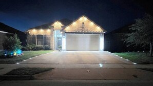 Une maison à deux étages avec un garage, une façade en pierre et une entrée bien éclairée.