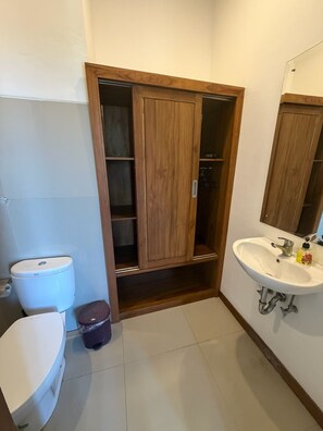 A bathroom with a toilet, a sink, and a wooden cabinet. - A quiet room with balcony in the heart of Ubud (Ubud)