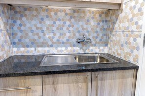 Eine Küche mit einem sechseckig gemusterten Rückwand, einer Edelstahlspüle und Holzschränken.