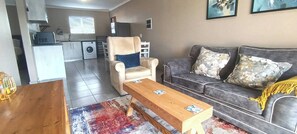 Een woonkamer met een bank, fauteuil, salontafel en vloerkleed.