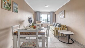 Un coin repas avec une table dressée pour deux personnes, un canapé et une petite table ronde.