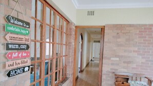 Un pasillo con un banco de madera, una pared de ladrillo y un cartel con flechas direccionales.