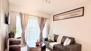 Una sala de estar moderna con un sofá, una mesa de centro y un televisor montado en la pared.
