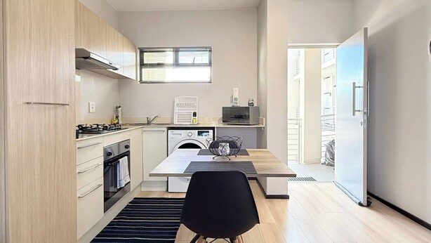 Una cocina moderna con armarios de madera, una mesa de comedor y una silla negra.