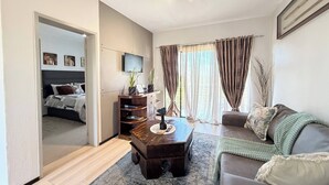 Una sala de estar moderna con sofá, mesa de centro, televisor y estantería.