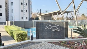 Un edificio moderno con un letrero que dice 'SoHo Junction' y una piscina.