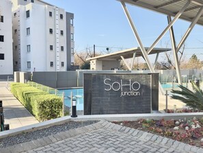 Ein modernes Gebäude mit einem Schild, auf dem 'SoHo Junction' steht, und einem Schwimmbecken.