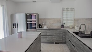 Una cocina moderna con una isla central, horno empotrado y un lavamanos con ventana arriba.