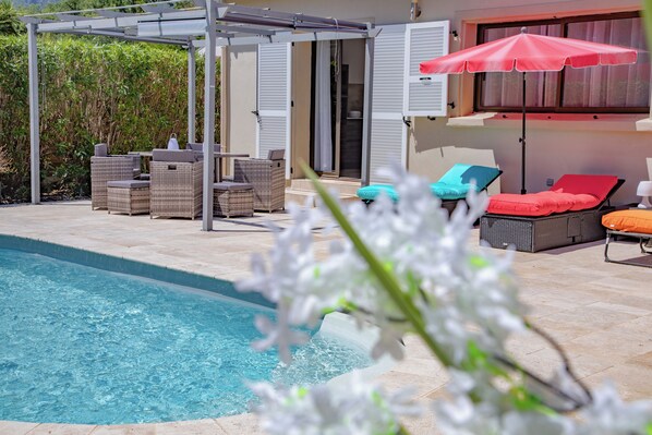 A poolside area with wicker furniture, a pergola, and a red umbrella. - A Casa Serena: The soul of Corsica in a picturesque setting... (Santa-Maria-Poggio)