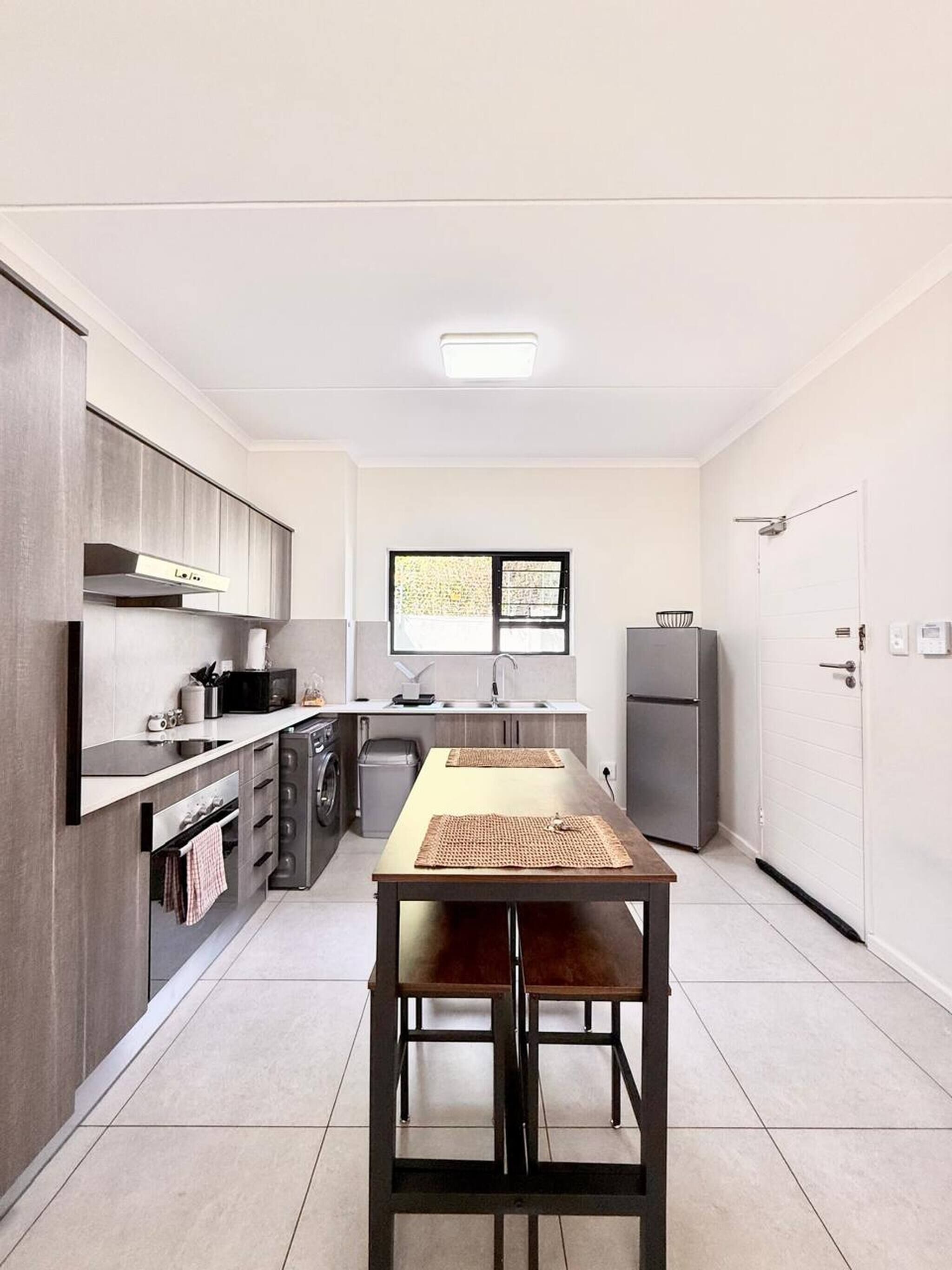 A modern kitchen with a dining table, built-in appliances, and a window.