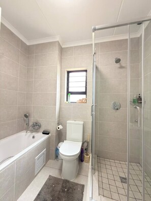 Moderni kylpyhuone, jossa on kylpyamme, wc ja suihku.