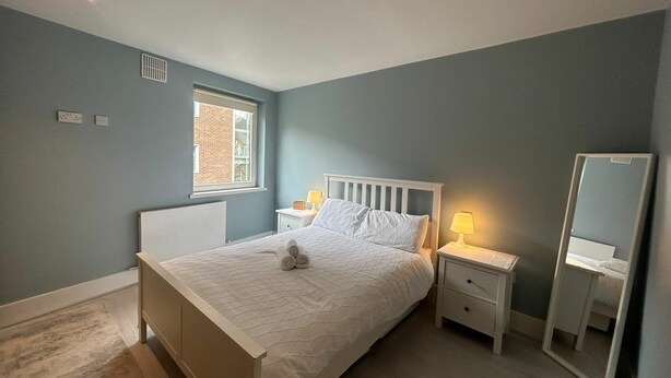 Een slaapkamer met een bed, nachtkastjes, een spiegel en een raam.