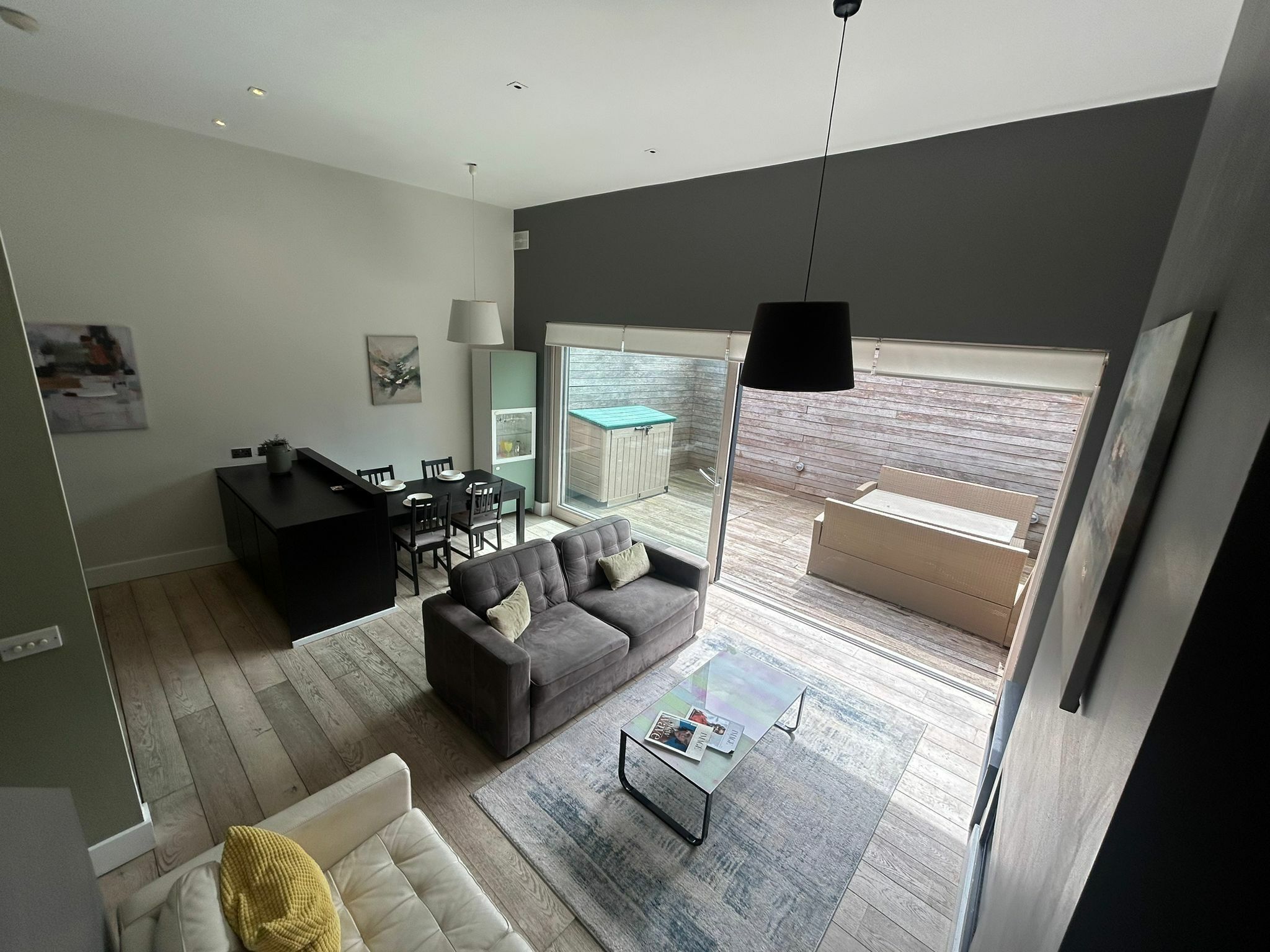 A modern living room with a sofa, coffee table, and a dining area with chairs and a table.
