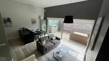 A modern living room with a sofa, coffee table, and a dining area with chairs and a table.
