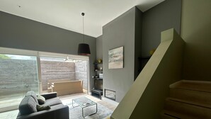 Een moderne woonkamer met een bank, salontafel en een trap naar een verdieping erboven.
