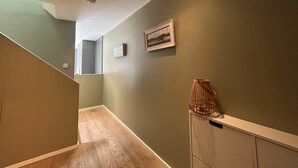 Een hal met een houten vloer, een radiator en een lijst met een afbeelding aan de muur.