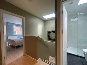 Ein modernes Badezimmer mit Duschkabine aus Glas, einer sichtbaren Toilette und einem kleinen Spiegel an der Wand.