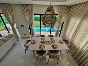 A dining area with a table, chairs, and a hanging light fixture. - Welcome to Villa Lina (Punta Cana)