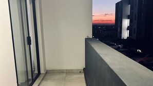 A balcony with a view of the sunset, a door with a glass panel, and a welcome mat. - Cozy Apartment in the heart of Joburg. (Midrand)