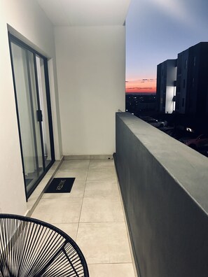 Parveke, jolta avautuu näkymä auringonlaskuun, lasipaneelilla varustettu ovi ja tervetulomatto.
