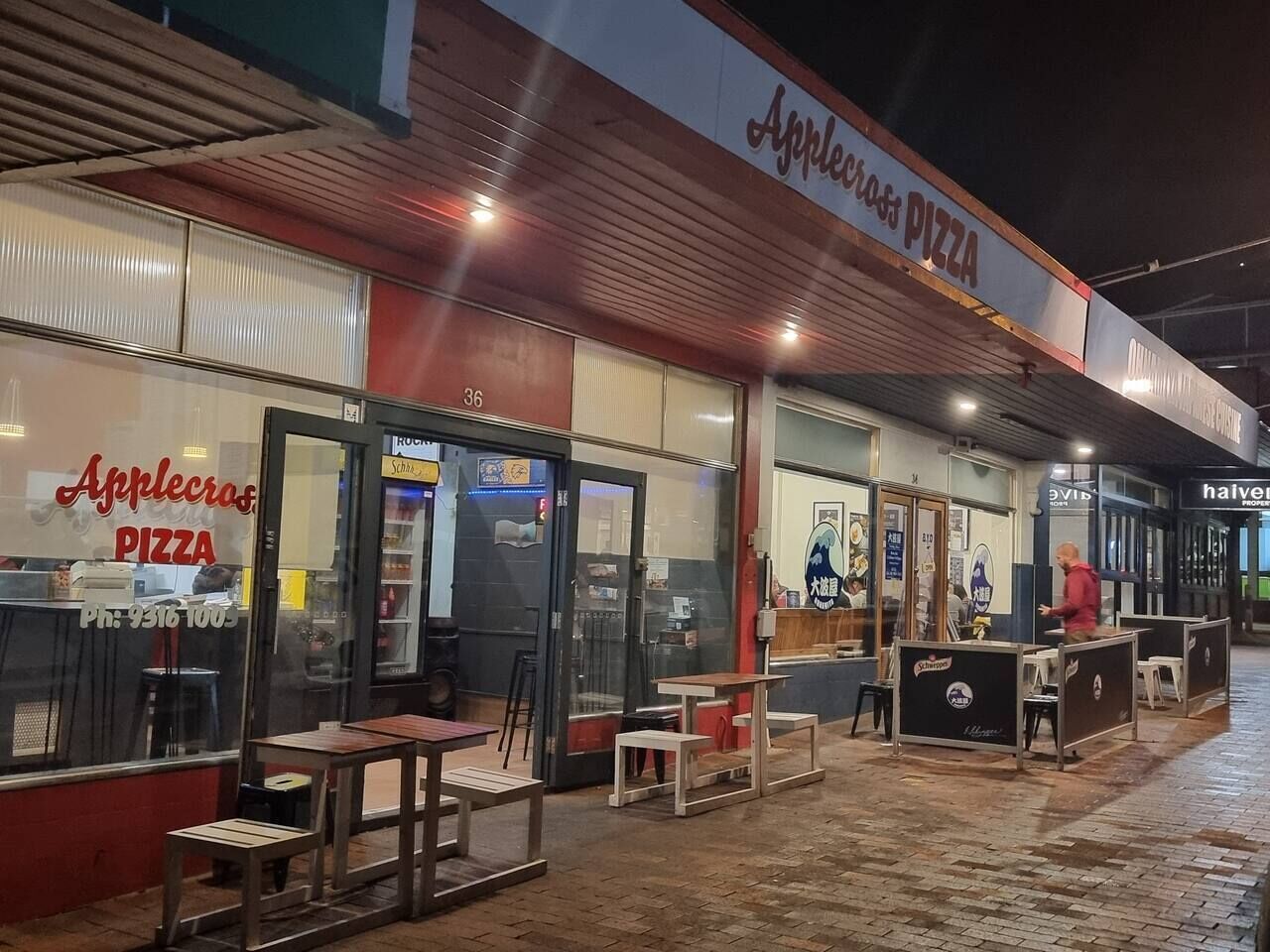 Ein Pizzarestaurant mit Außenbereich, einer Schautafel und einer Schaufensterfront.