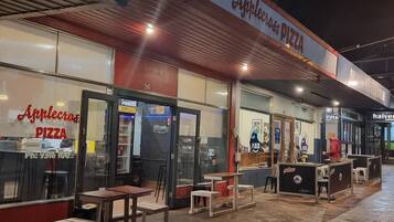 Ein Pizzarestaurant mit Außenbereich, einer Schautafel und einer Schaufensterfront.