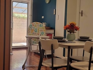 Uma sala de jantar com uma mesa, cadeiras e um vaso de flores.