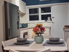 Una cucina con frigorifero, fornello e un tavolo da pranzo con un vaso di fiori.