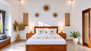 A bedroom with a wooden bed, two bedside tables with lamps, a large window with curtains, and wall art. - Togog Sebatu Villa (Gianyar)